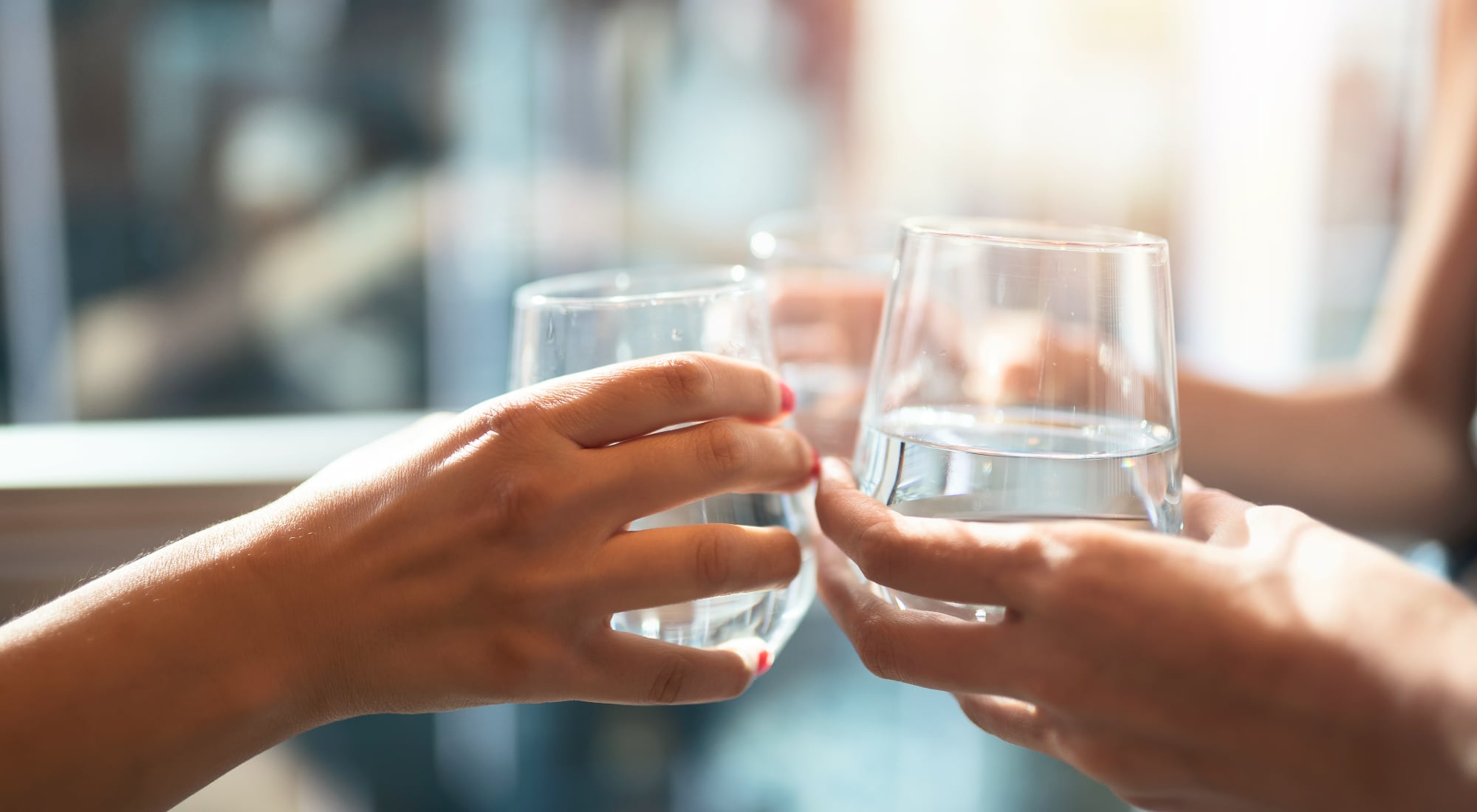 Two people are toasting with glasses that have clear, pure water in them.